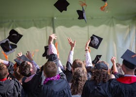 Group of graduates celebrating by tossing caps into the air during a graduation ceremony.